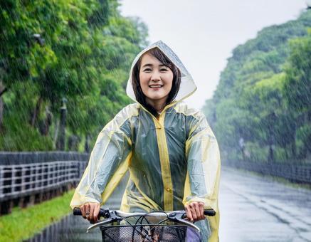 レインコートを着て自転車に乗る女性 レインコートを着て自転車に乗る女性の写真