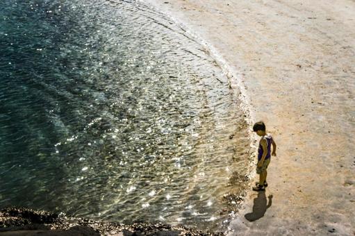 <素材>夏の浜辺を歩く小学生の男の子 <素材>夏の浜辺を歩く小学生の男の子の写真