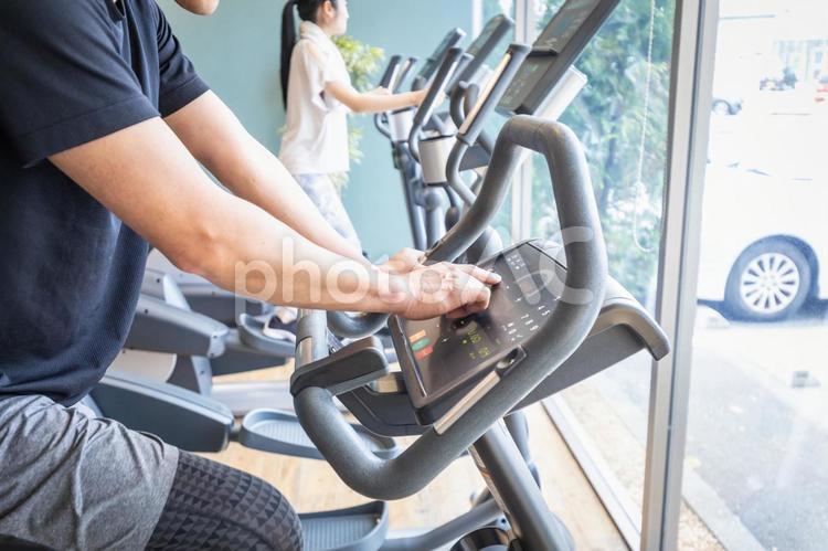 エアロバイクで運動する男性（顔なし） エアロバイク,スポーツジム,ランニングマシンの写真素材