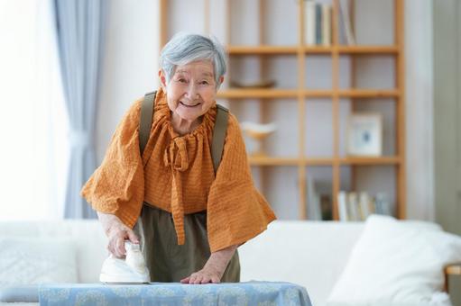 リビングでアイロン掛けをする高齢女性 女性,アイロン,アイロン台の写真素材