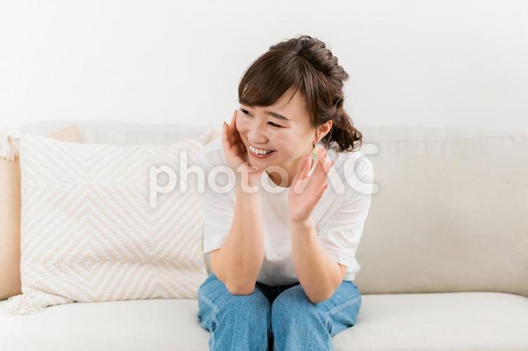 家のソファで会話して楽しそうな日本人女性 女性,笑顔,手を振るの写真素材