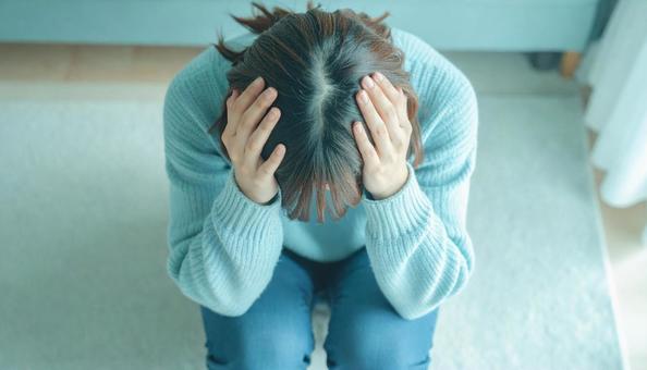 頭を抱えて落ち込む日本人女性 頭を抱えて落ち込む日本人女性の写真