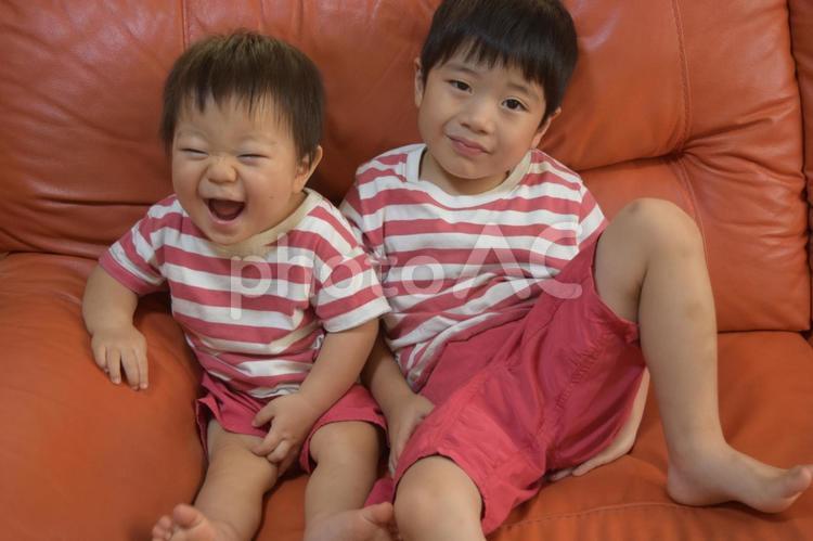 オレンジ色のソファーに座る仲良し兄弟 幼児,男,子供の写真素材
