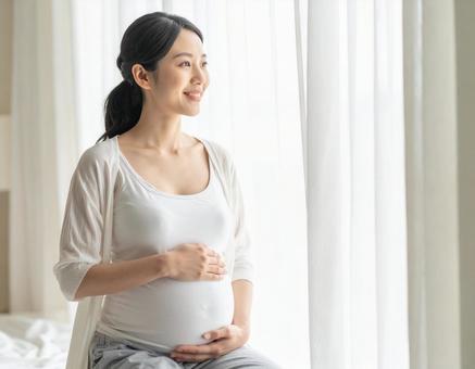 窓辺で外を見て微笑む妊婦の穏やかな時間 窓辺で外を見て微笑む妊婦の穏やかな時間の写真