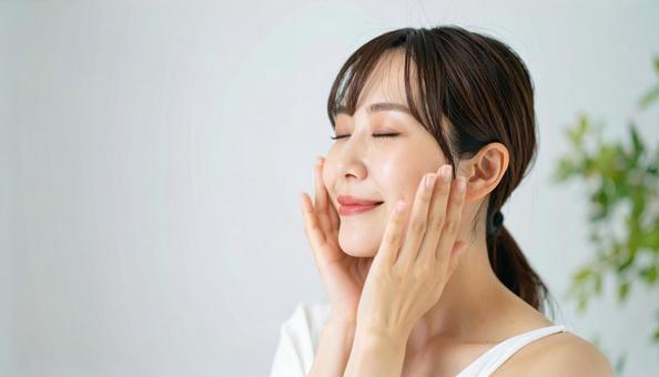 ほほをさわり満足して目をつむる若い女性 ほほをさわり満足して目をつむる若い女性の写真