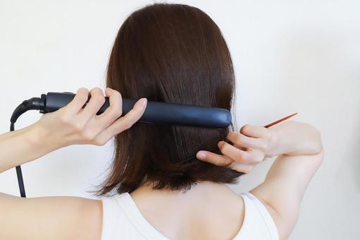 ストレートアイロンを使う女性 ストレートアイロンを使う女性 ストレートアイロン,ヘアアイロン,ヘアスタイリングの写真素材