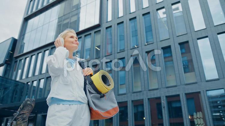 ヘッドフォンをしてヨガマットを持っている女性 女性,人物,元気の写真素材
