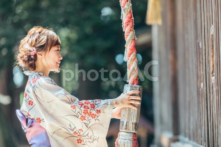 お参りして鈴を鳴らす浴衣姿の女性 神社,お参り,鈴の写真素材