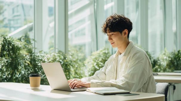 明るいオフィスで作業する男性 明るいオフィスで作業する男性の写真
