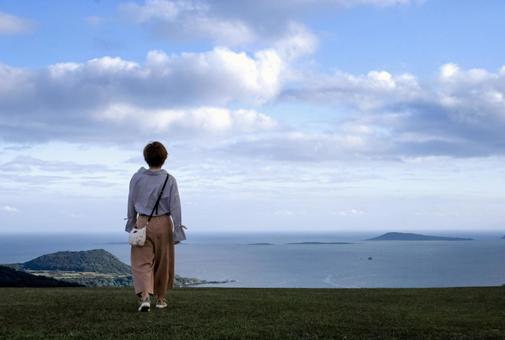 ＜素材＞山頂を散歩する女性の後ろ姿 女性,海,空の写真素材