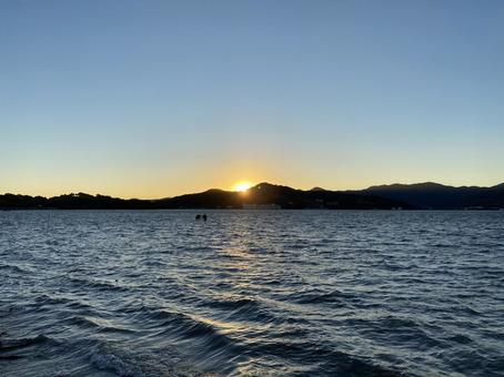 風が強く吹く湖の対岸の山に夕陽が沈む 風が強く吹く湖の対岸の山に夕陽が沈む 湖,雲,初夏の写真素材