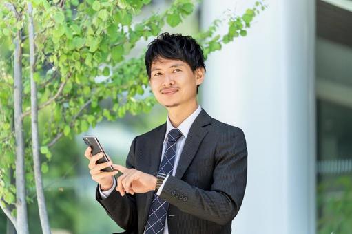 オフィス街でスマホを使う男性ビジネスマン オフィス街でスマホを使う男性ビジネスマン 男性,スマホ,スマートフォンの写真素材