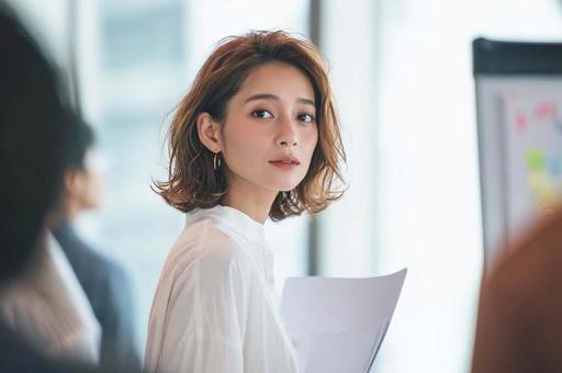 会議で資料を説明する女性 会議で資料を説明する女性の写真