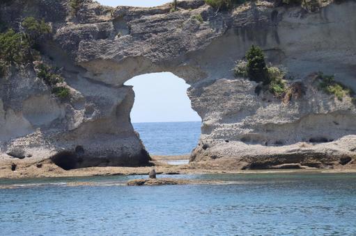 青い海面の海と穴の開いた岩壁のある風景 青い海面の海と穴の開いた岩壁のある風景の写真