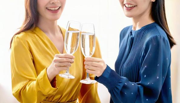 シャンパンで乾杯する笑顔の女性2人の手元 シャンパンで乾杯する笑顔の女性2人の手元の写真