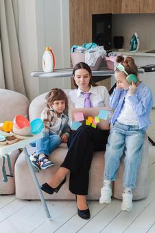 ビジネスウェアで我が子に挟まれ働くお母さん 親子,女性,ノートパソコンの写真素材