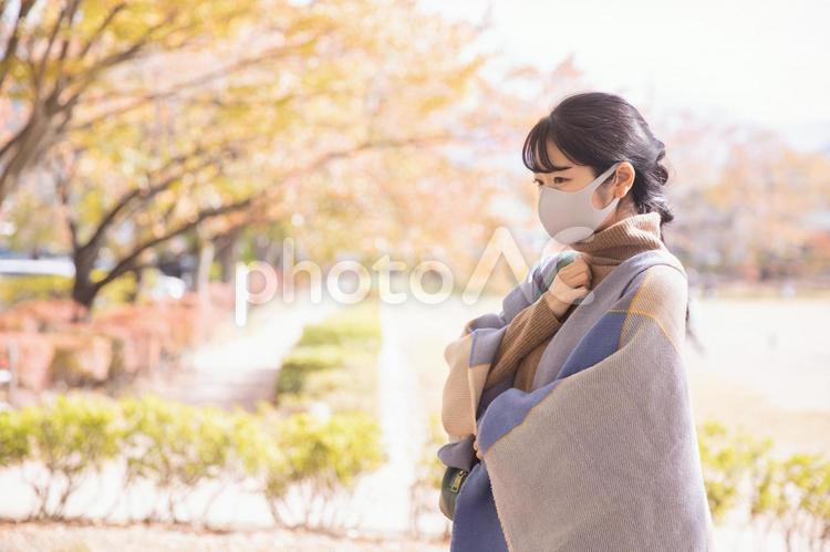 秋の公園でマスクをつけて咳き込む女性 マスク,コロナ,肺炎の写真素材