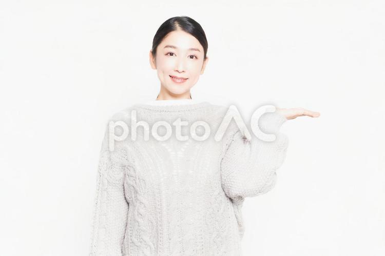 白い背景の前に立って案内をするセーターを着ている主婦 案内,主婦,女性の写真素材