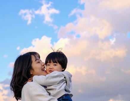 青空の下、子供を抱っこする母親 青空の下、子供を抱っこする母親の写真