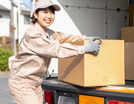 トラックから荷物を出す宅配女性ドライバー トラックから荷物を出す宅配女性ドライバーの写真