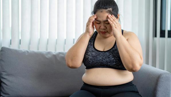 肥満で疲れやすく、額に手をやる女性 肥満で疲れやすく、額に手をやる女性の写真
