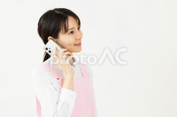 電話をするエプロン姿のアジア人女性03 保育士,女性,エプロンの写真素材
