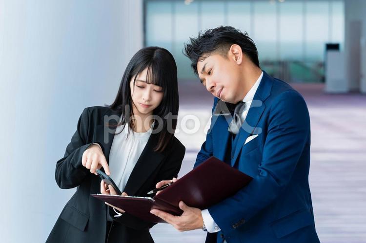 電話している先輩に携帯を見せる後輩 ビジネスウーマン,ビジネスマン,女性の写真素材