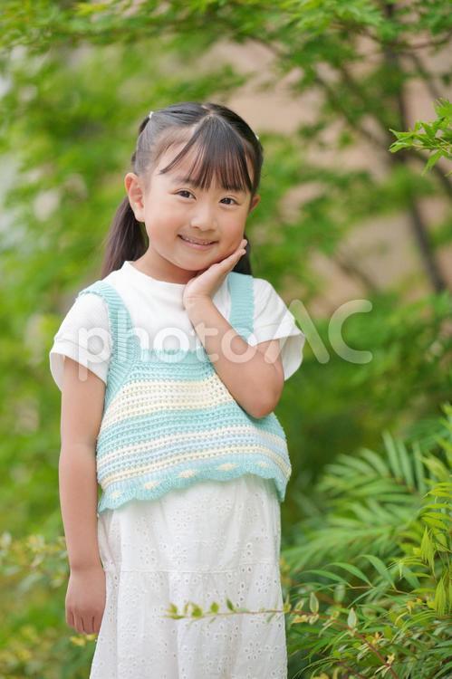 緑をバックにカメラ目線の女の子 女の子,女児,カメラ目線の写真素材