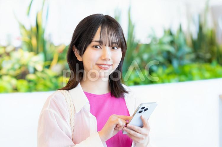 スマホを見る笑顔の女性 スマホ,若い女性,笑顔の写真素材