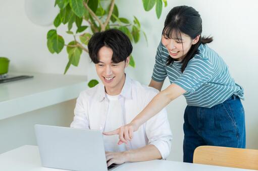 パソコンを見るカップル ノートパソコン,笑顔,カップルの写真素材