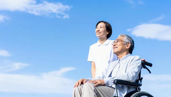 青空を見つめる車いすシニアと介護の女性 青空を見つめる車いすシニアと介護の女性の写真