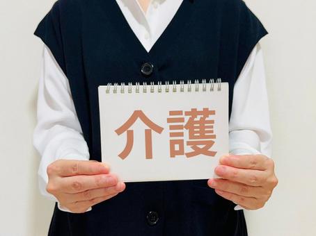 介護と書かれたノートを掲げる女性介護士 介護と書かれたノートを掲げる女性介護士の写真