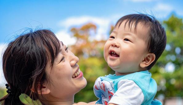 青空の下、子供を抱っこする母親 青空の下、子供を抱っこする母親の写真