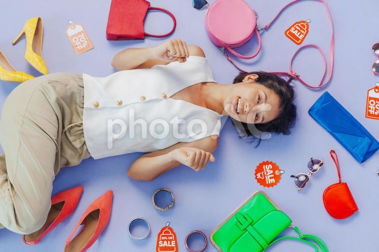 寝転ぶアジア人女性とセールのタグとファッション小物 セール,ショップ,女性の写真素材