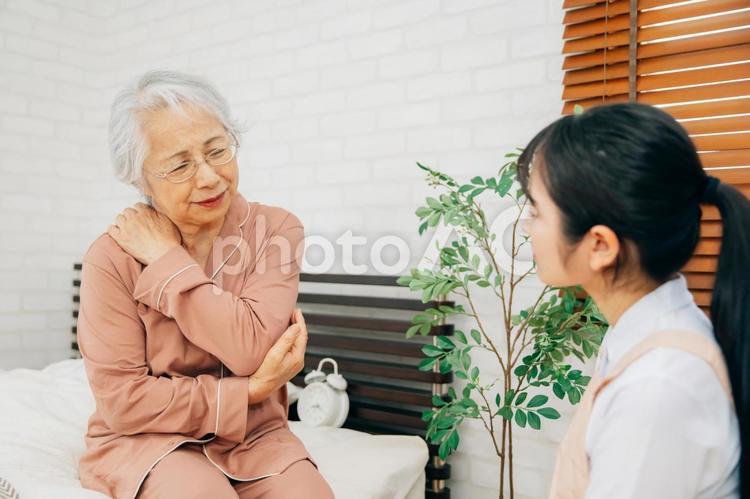 痛がる高齢者女性とエプロン姿の女性（肩こり） 肩こり,肩凝り,肩の写真素材