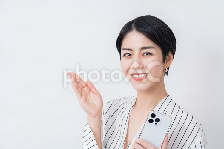 スマホを持った提案するビジネスパーソン。 ビジネスウーマン,女性,キャリアウーマンの写真素材