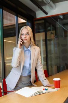 立ち上がって電話している真剣な表情のビジネスウーマンの写真
