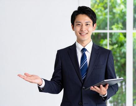 タブレットを片手に案内する男性 タブレットを片手に案内する男性の写真