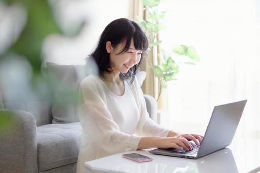 Image of a young woman operating a smartphone and a computer Image of a young woman operating a smartphone and a computer