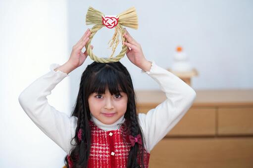 頭上で正月飾りを持つ笑顔の女の子 女の子,しめ縄,締め飾りの写真素材