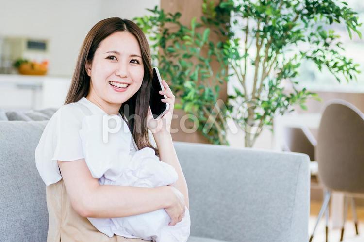 赤ちゃんを抱きながら通話する女性 赤ちゃん,ママ,子育ての写真素材