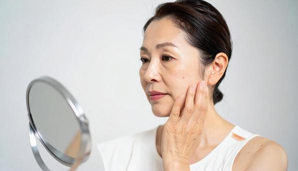 ほうれい線を気にして肌を触る中年の女性 ほうれい線を気にして肌を触る中年の女性の写真
