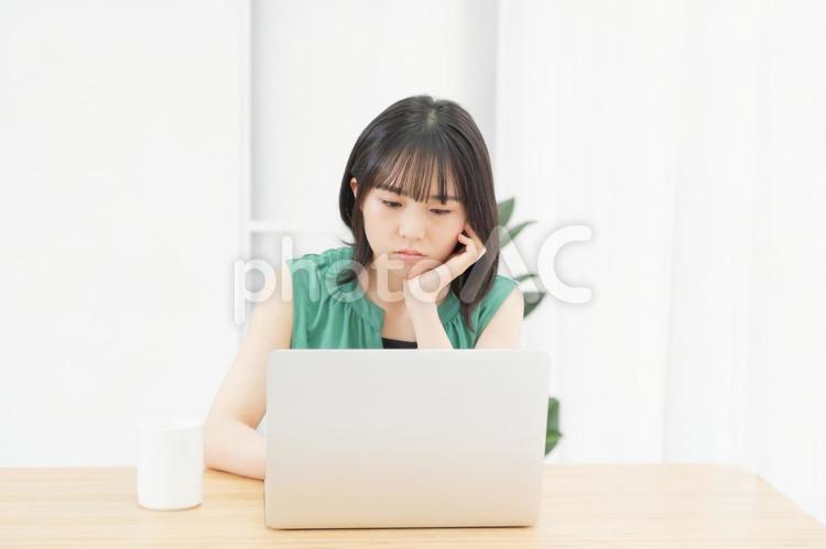 肘をついて考え事をしている若い女性 ノートパソコン,パソコン,女性の写真素材