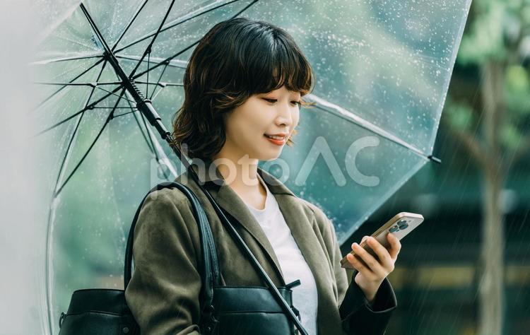 傘をさしてスマホを使う女性（梅雨・6月） 雨,梅雨,6月の写真素材