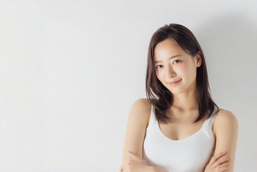 美肌の女性が自然な笑顔で腕を組んで立つ姿の写真
