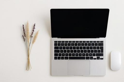 白いデスク上のノートPCとドライフラワー 白いデスク上のノートPCとドライフラワーの写真