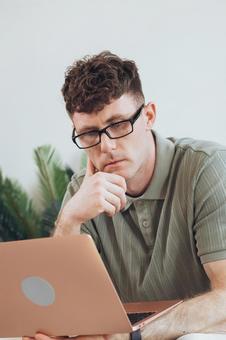 椅子に座って手に持ってノートパソコンを使う男性 男性,外国人,欧米人の写真素材