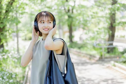 新緑の中ヘッドフォンで音楽を聴く若い女性 新緑の中ヘッドフォンで音楽を聴く若い女性 女性,外出,ヘッドフォンの写真素材