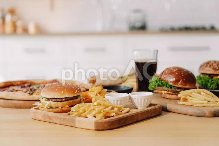 キッチンにたくさんのジャンクフード ハンバーガー,ピザ,ナチョスの写真素材