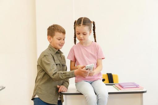 携帯を一緒に見る携帯を一緒に見る仲良しな生徒たち 男の子,女の子,子どもの写真素材